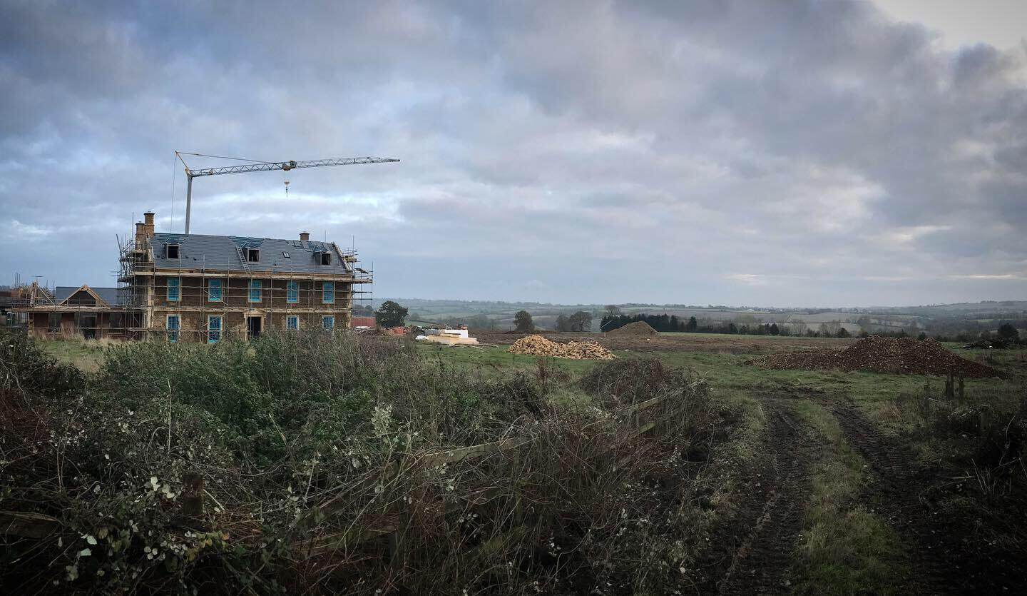 a Georgian new build farmhouse in the Cotswolds with crane over it