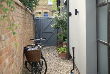 Old fashioned bike leaning against brick wall with garden gate