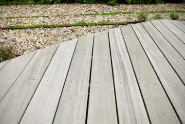 Close up shot of grey wooden decking with stones in back ground