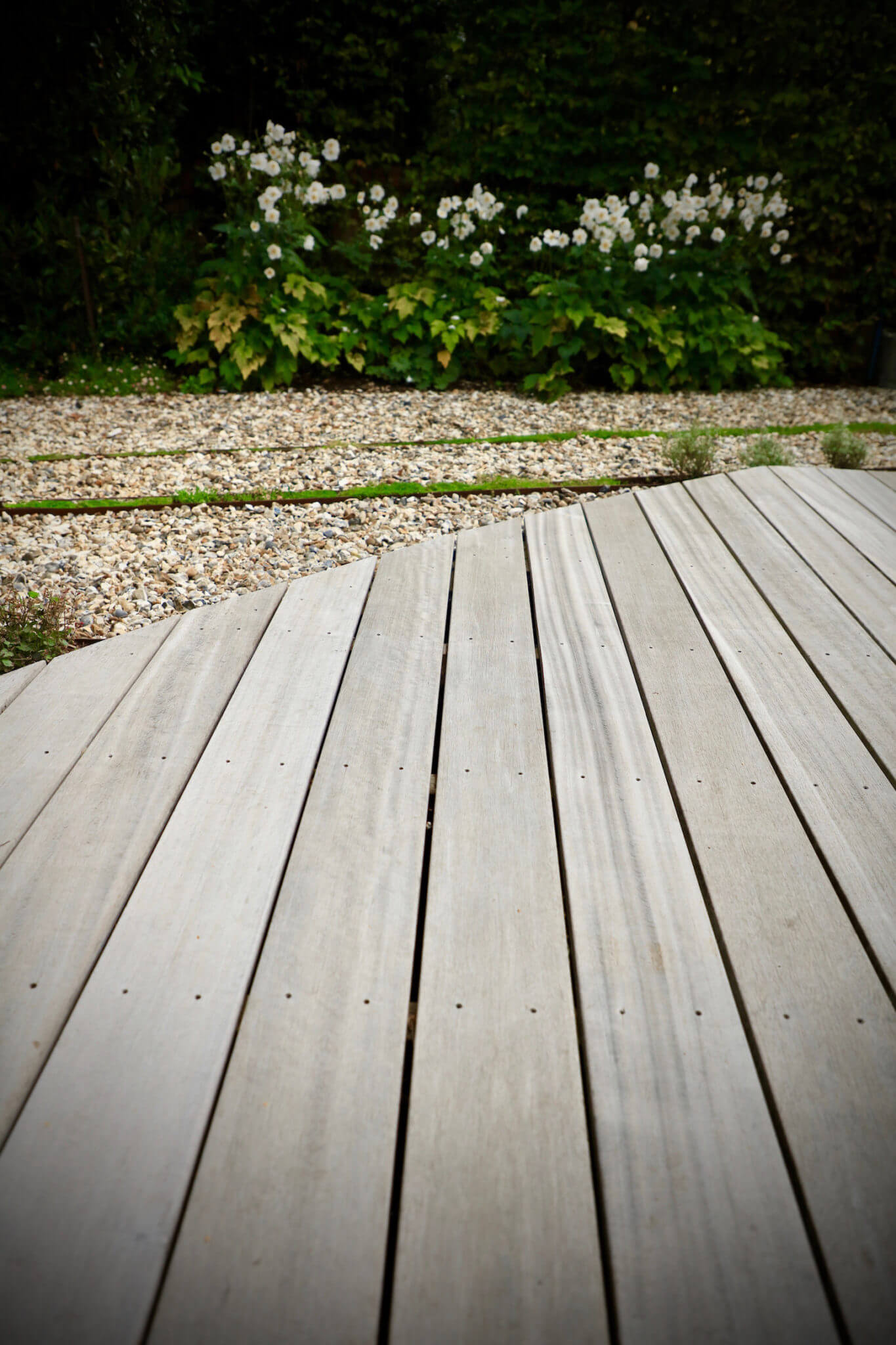 Close up shot of grey wooden decking with stones in back ground