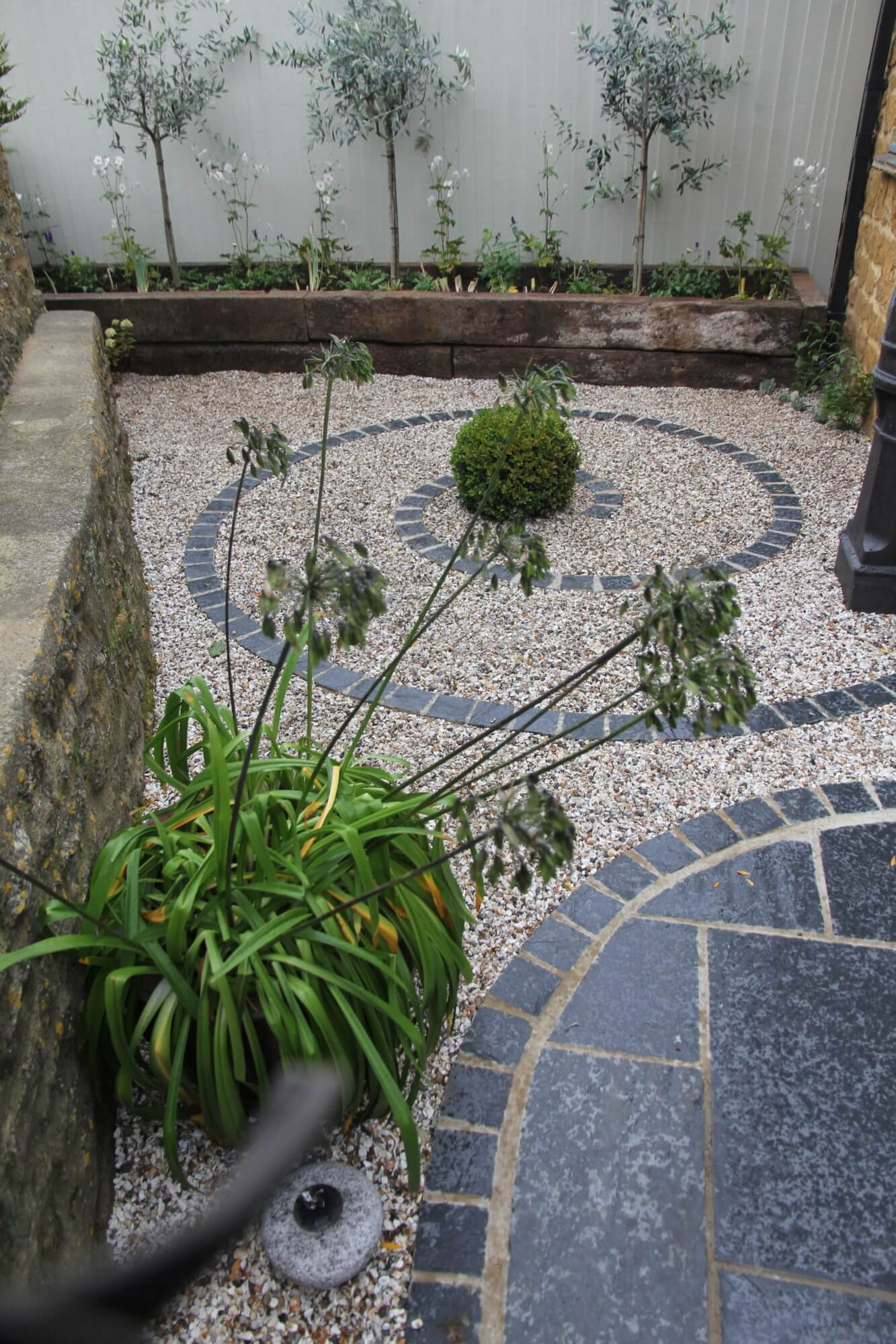 Snail pattern made from paving slabs in small garden