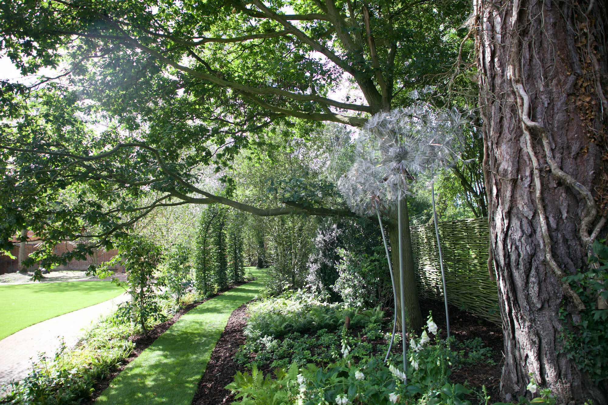 green lawn in a white woodland with dandelion sculpture