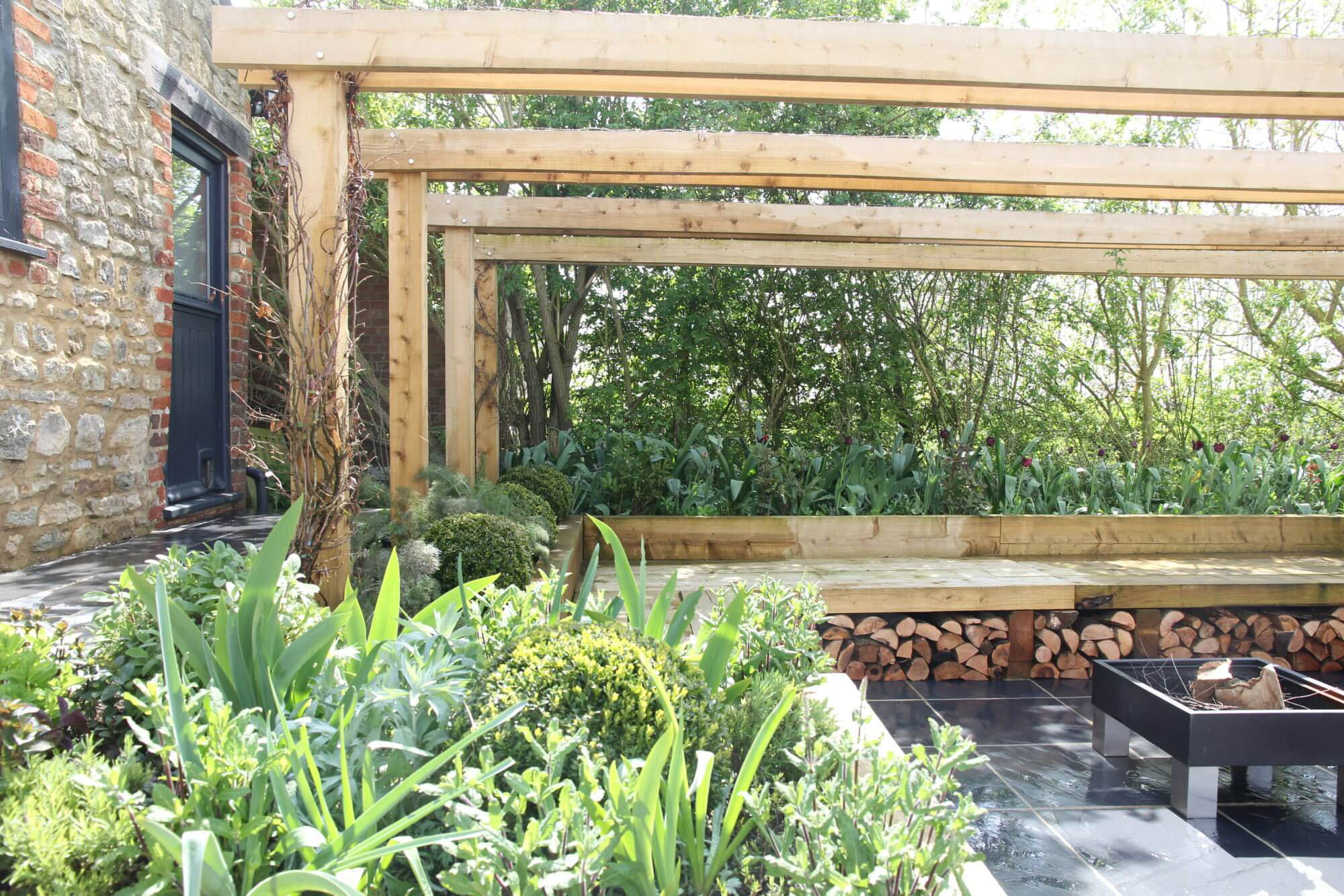 a sunken garden with wood pergola and seating and fire pit