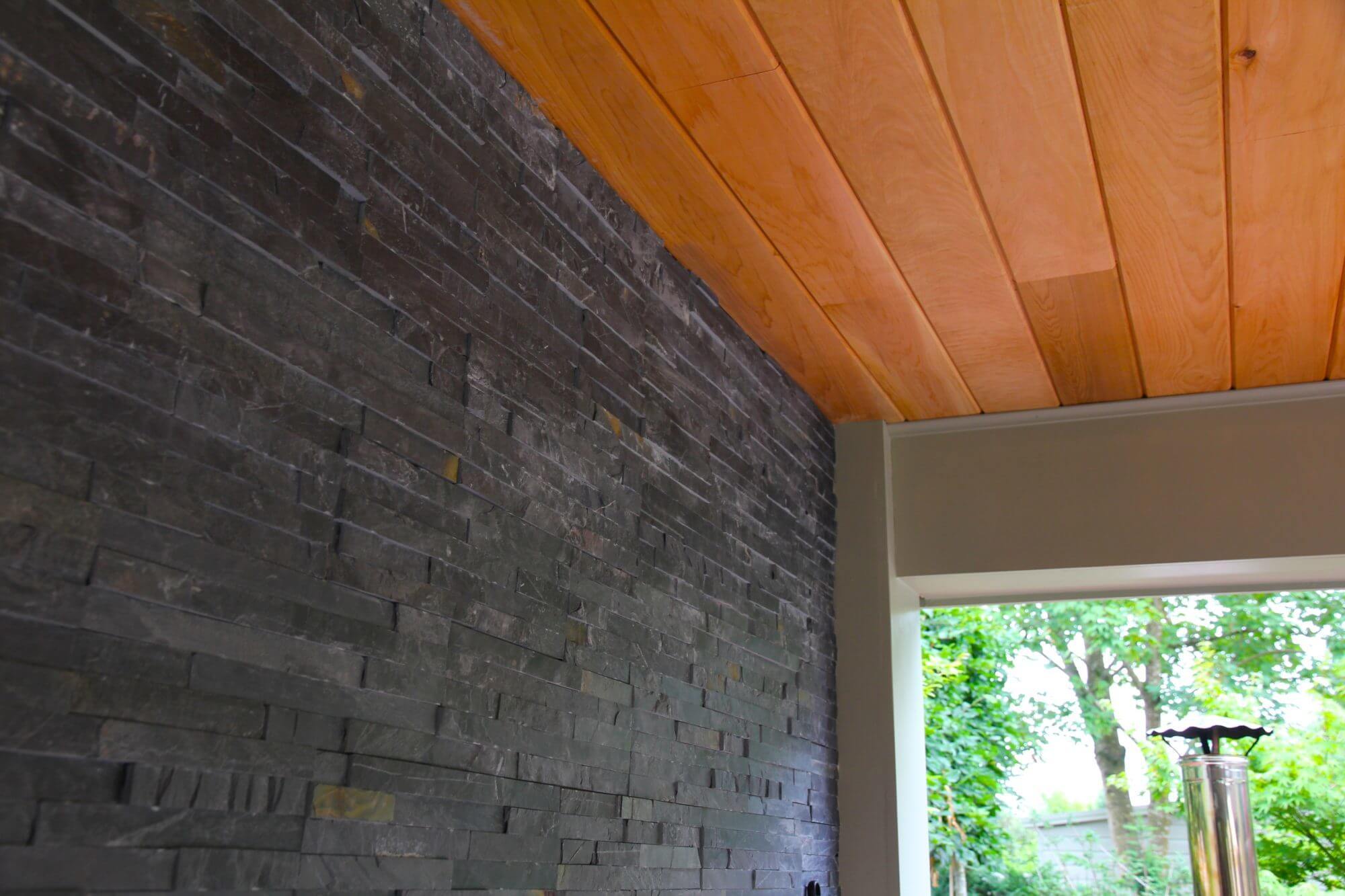 Slate walls inside garden cinema room with wooden ceiling