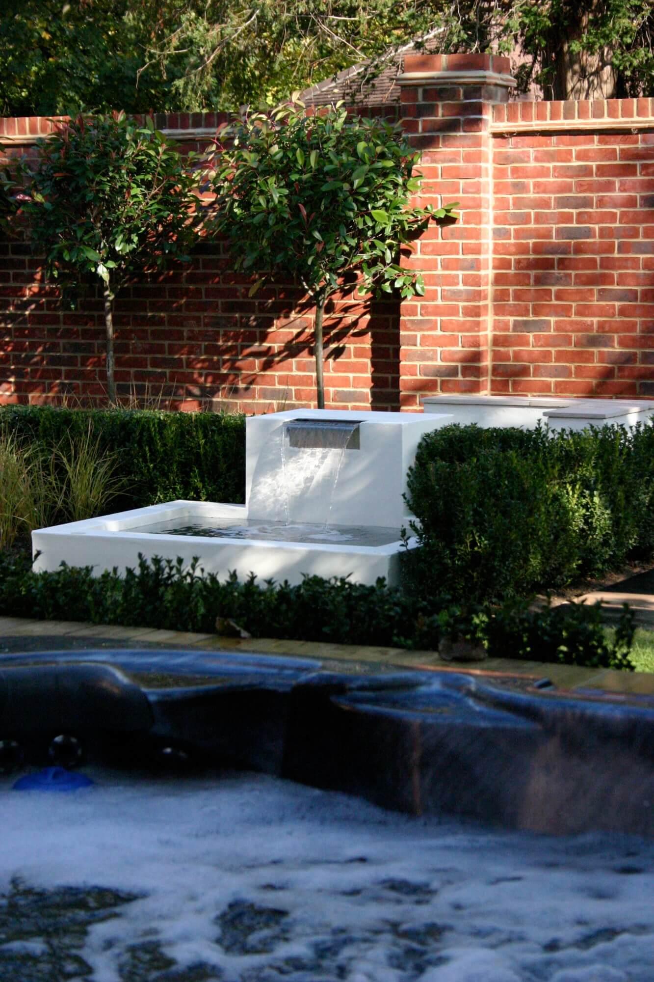Marble garden water feature in front of red brick wall