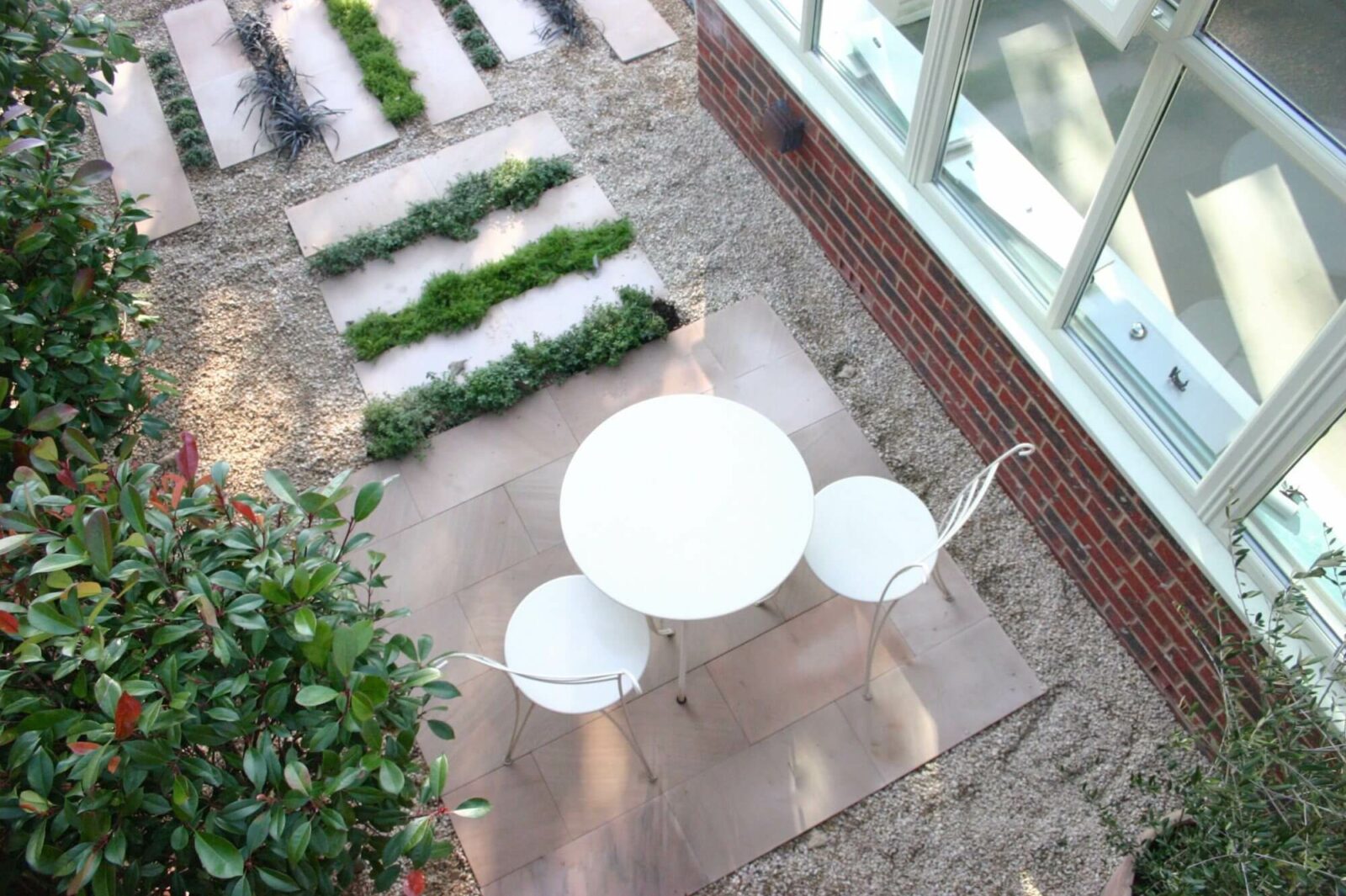 a small garden in oxfordshire with white paving and a cafe table