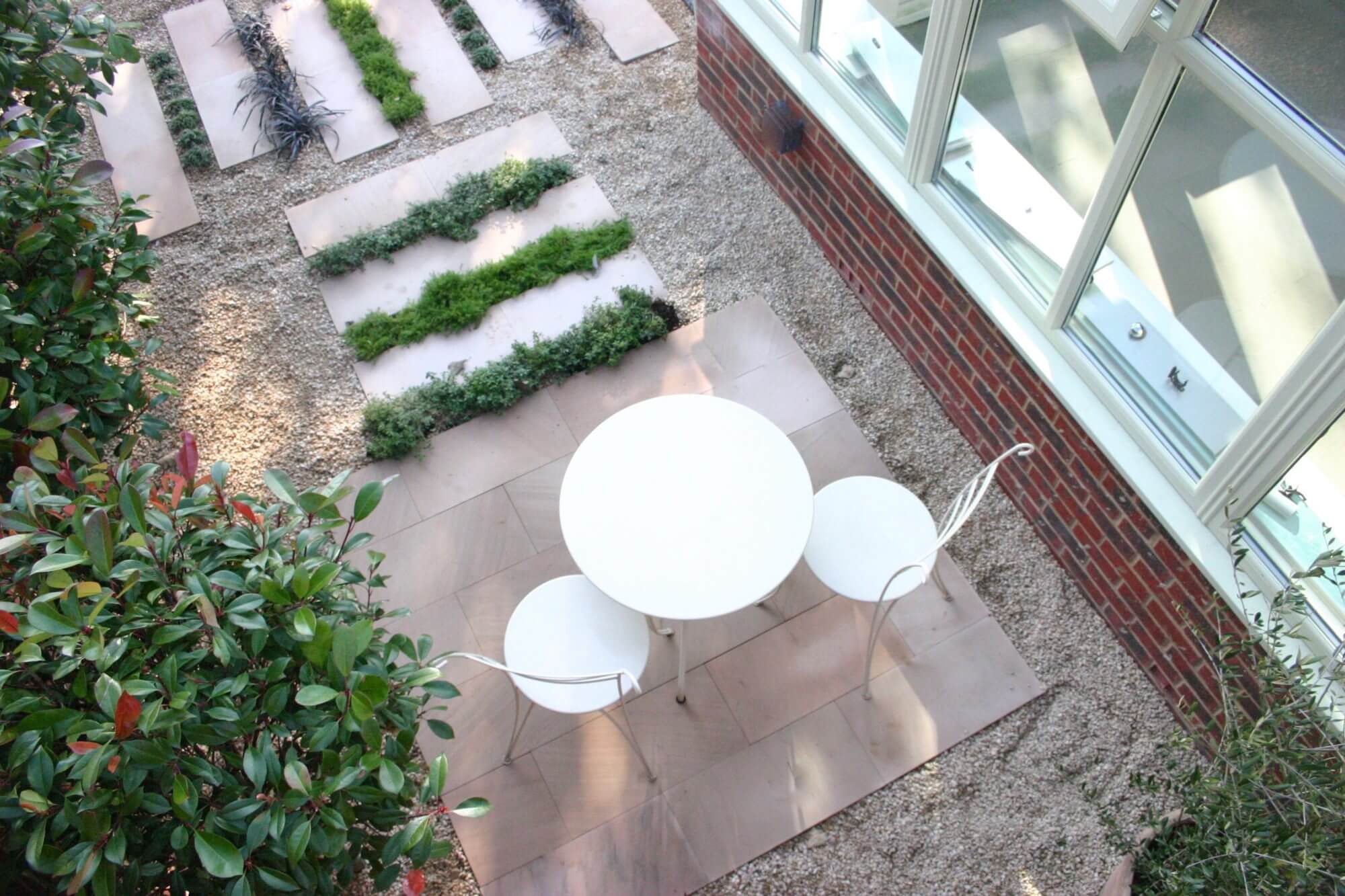 a small garden in oxfordshire with white paving and a cafe table