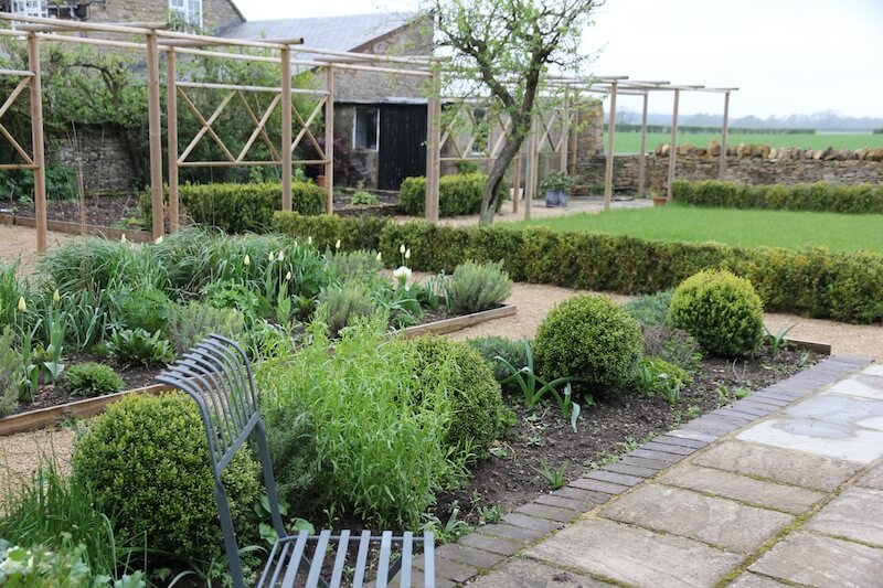 garden chair in front of a productive parterre garden with box balls