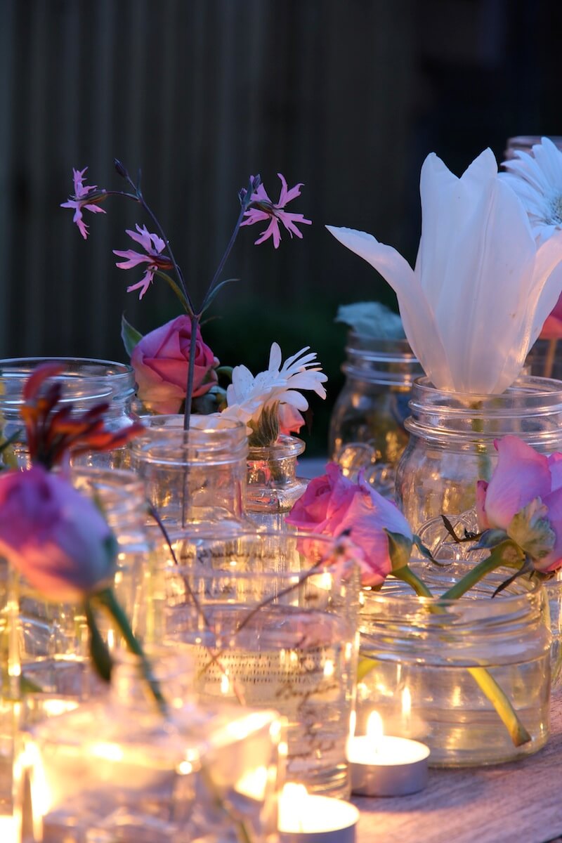 cut flowers in jars on a table in candlelight