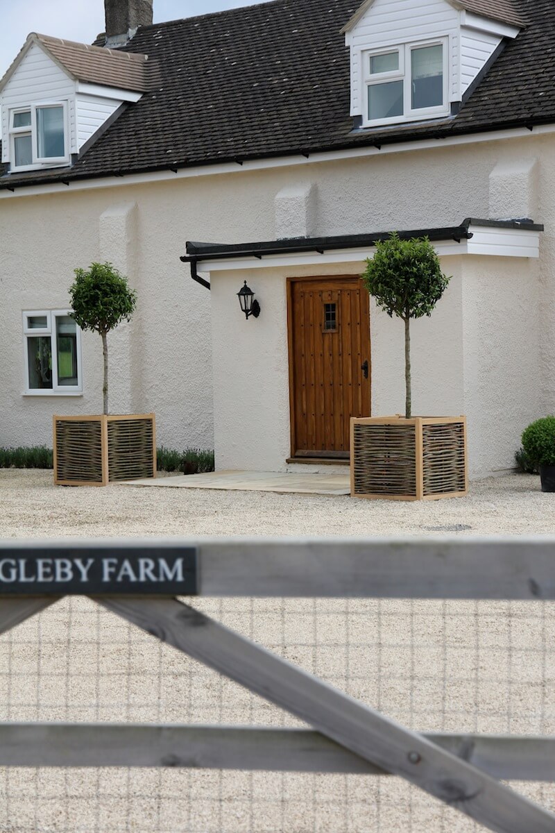 Tudor style front door with window, framed with two lollipop trees in square willow planters