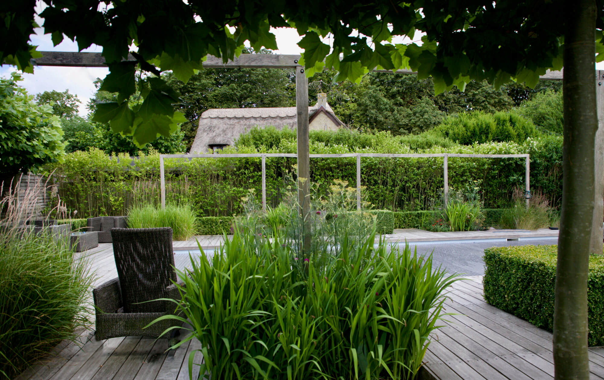 Cotswolds garden with swimming pool and thatched roof