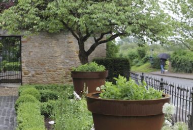 two big rust planters in front garden of oxford property with flowers