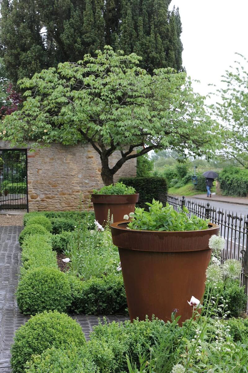 two big rust planters in front garden of oxford property with flowers