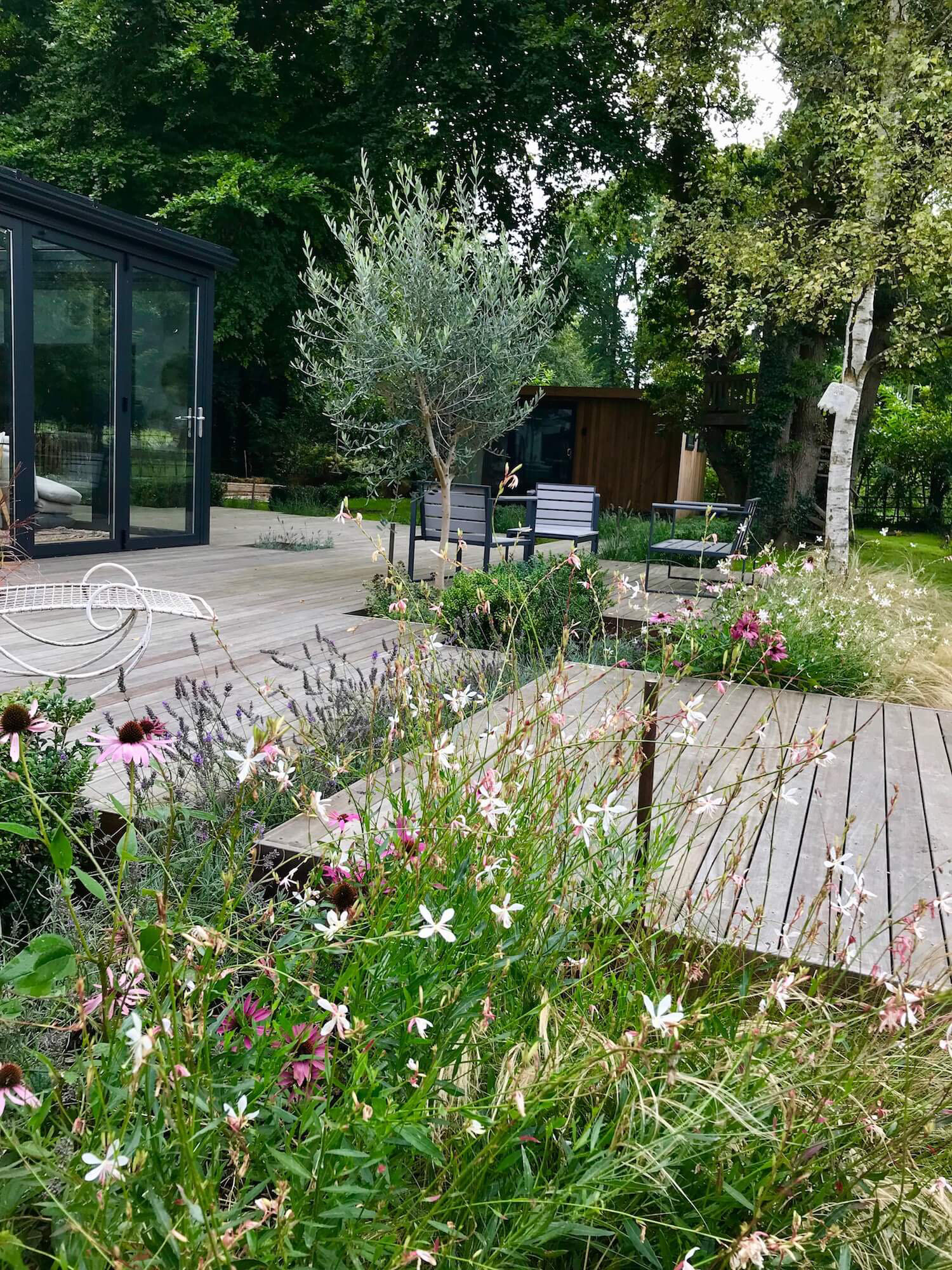 music studio in garden lakeside decked with colourful planting