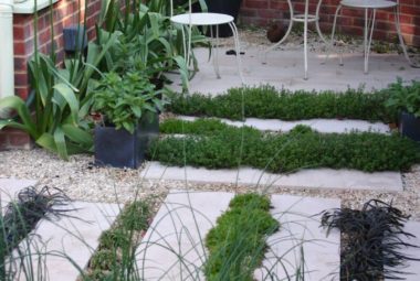 Stepp stones with planting in between and a white metal coffee table with two seats