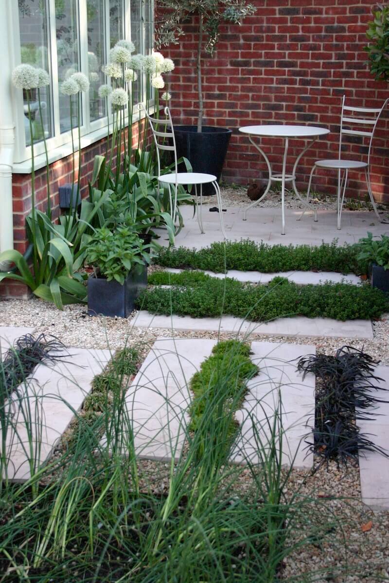 Stepp stones with planting in between and a white metal coffee table with two seats