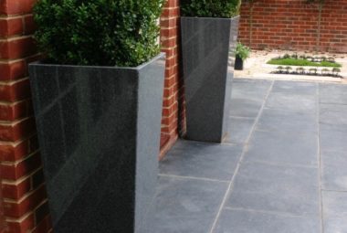 Cube topiary in grey granite planters against red brick wall