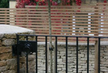 Black metal pedestrian gate leading to decking