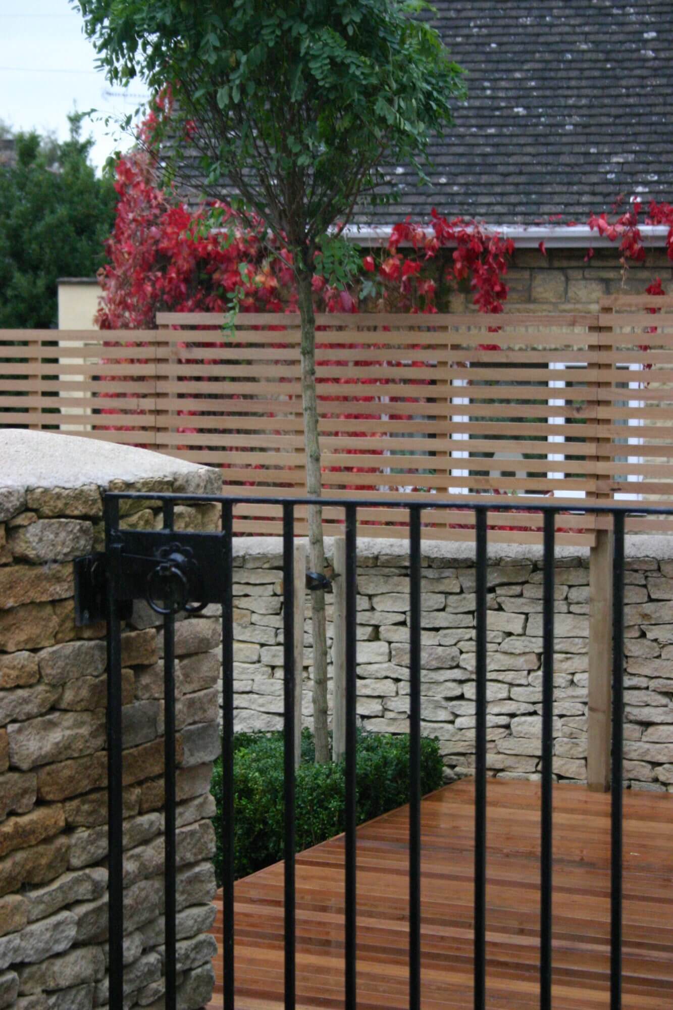 Black metal pedestrian gate leading to decking