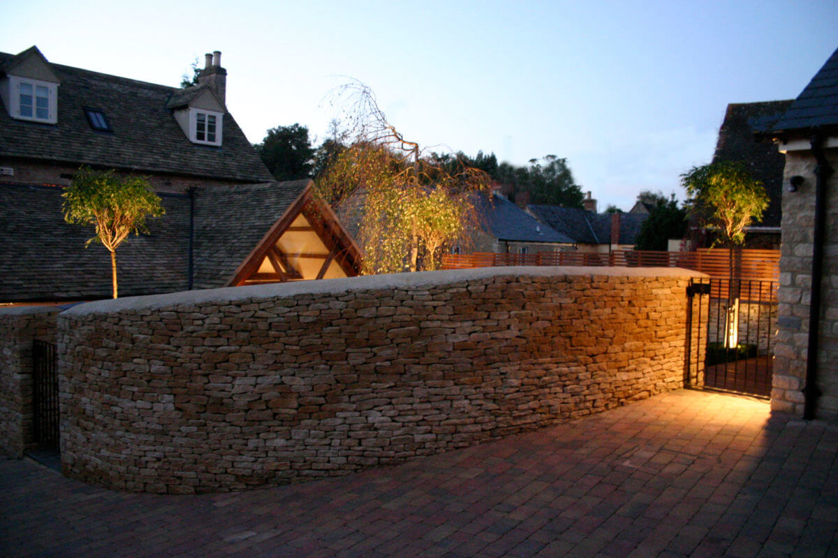 an Oxford garden at night with designer lighting on a dry stone wall