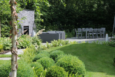 Topiary balls by outdoor furniture and a slate fire garden fireplace