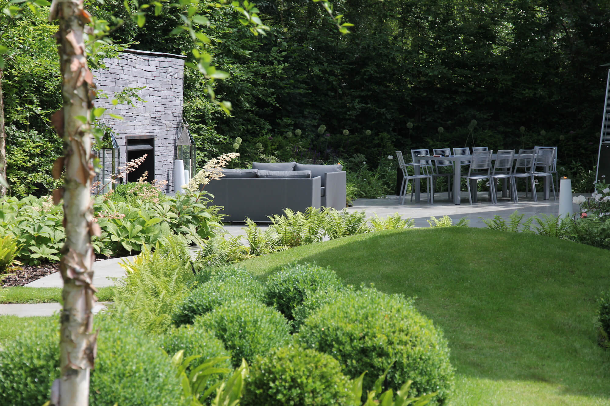 Topiary balls by outdoor furniture and a slate fire garden fireplace