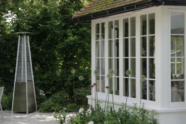 White alliums in front of big bay windows on patio with an outdoor heater