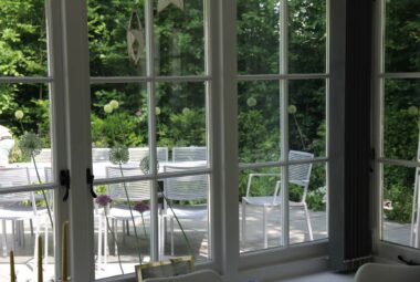 View of outdoor table and chairs through bay windows inside cottage