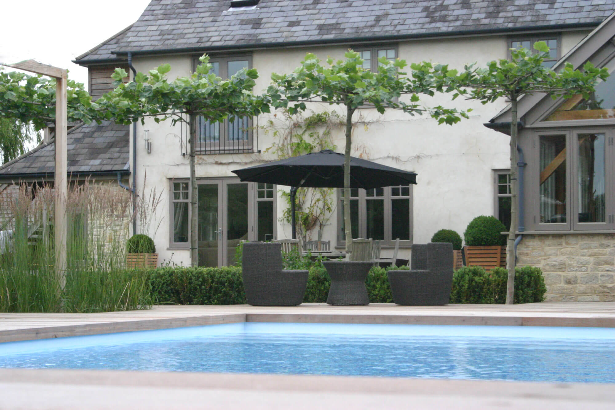 Cotswolds garden with swimming pool, farmhouse and manicured planting