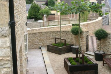 Pleached trees in wooden beds with moss and topairy