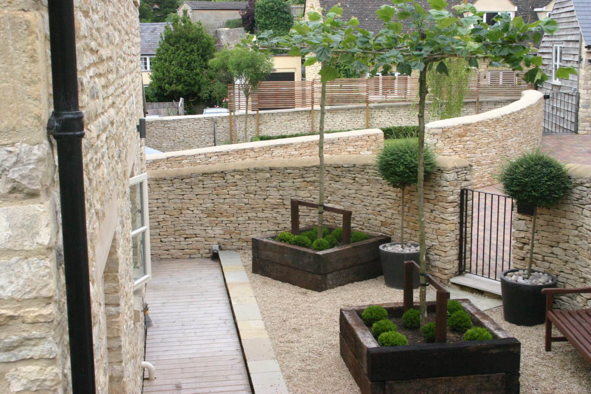 Pleached trees in wooden beds with moss and topairy