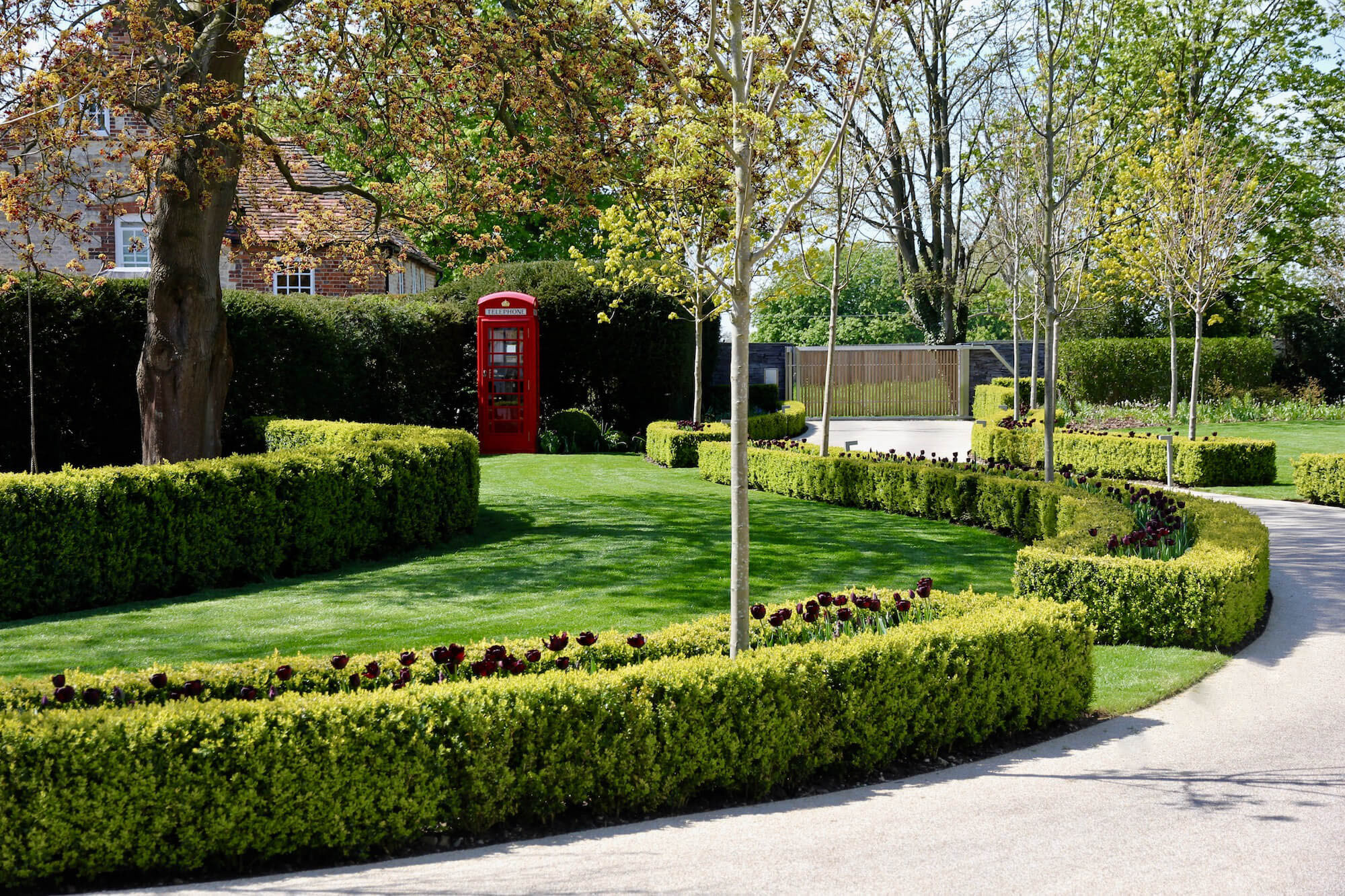 driveway and red English telephone box with black tulips in a landscape construction