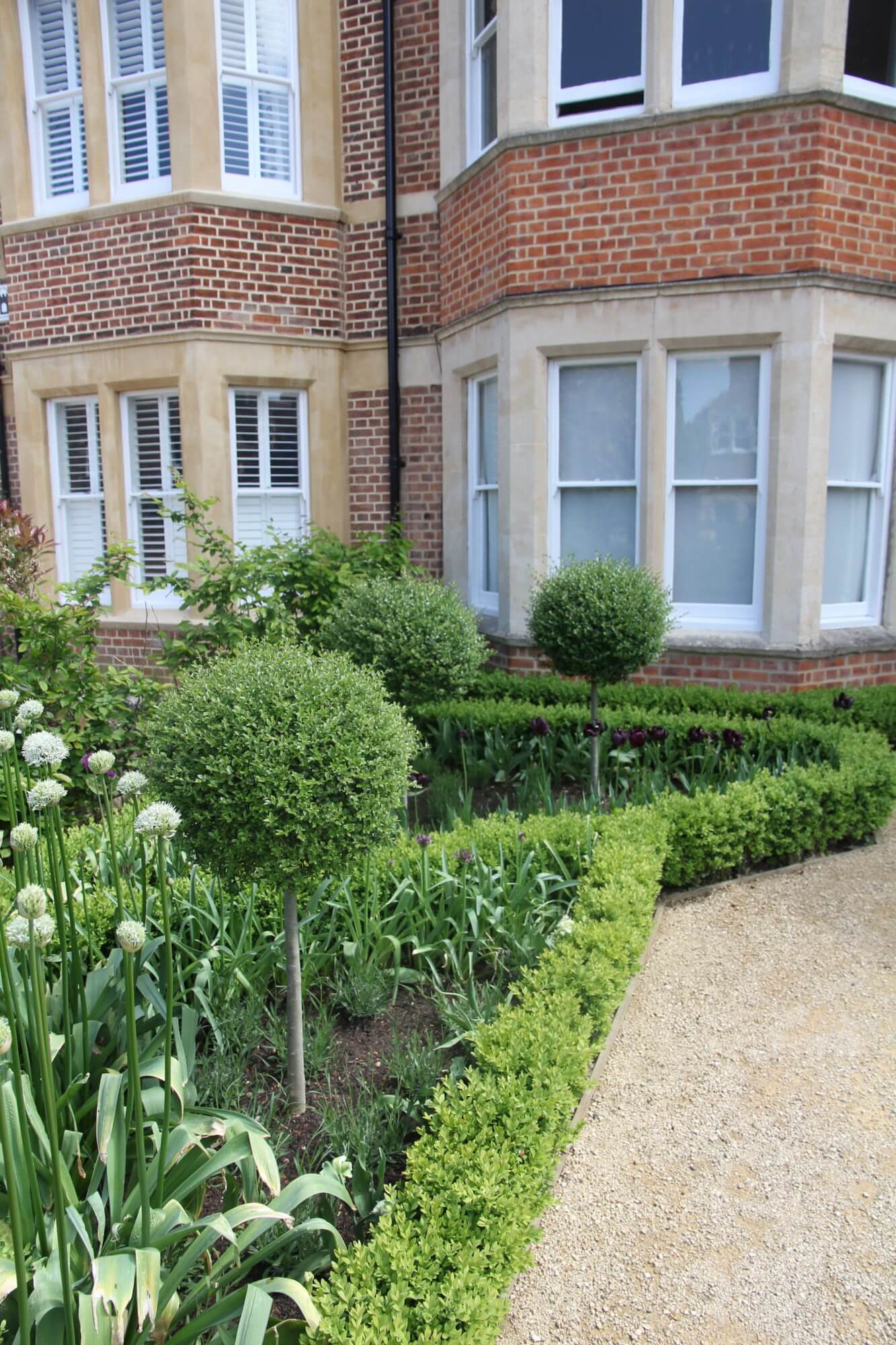 Red brick house with topiary front garden and bay windows