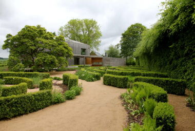 walled garden of curved planting and modern barn