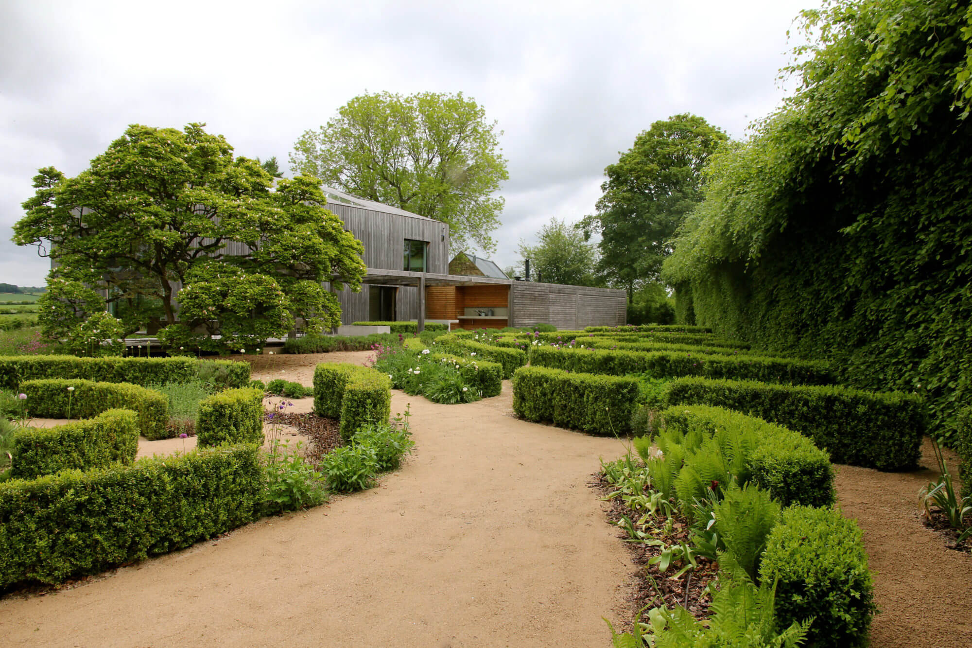walled garden of curved planting and modern barn