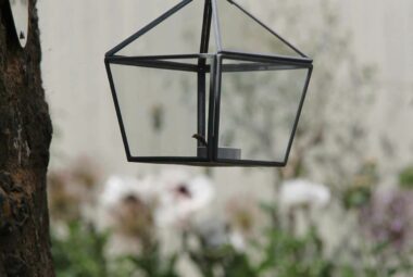 Hexagonal latern hanging from a chrome silver hook in tree