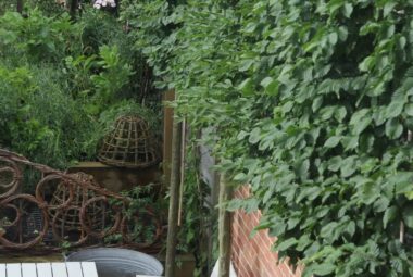 White wooden furniture next to red brick wall and willow woven fence