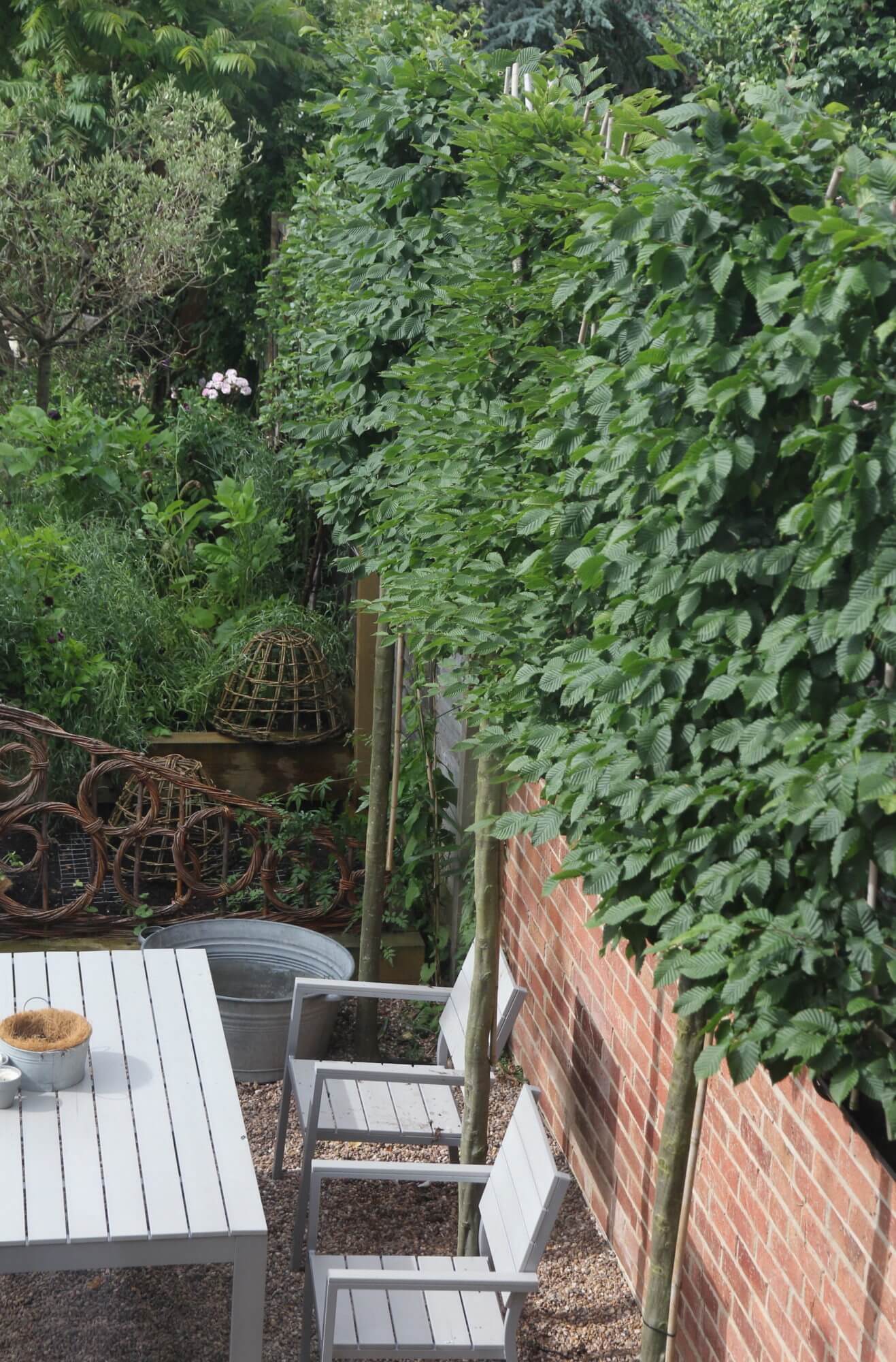 White wooden furniture next to red brick wall and willow woven fence