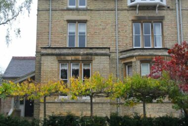 victorian building in oxford with pleached trees and topiary