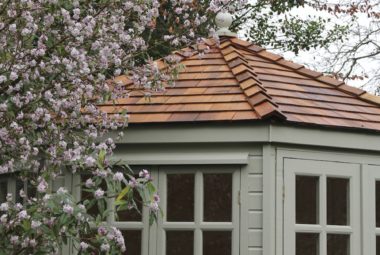 private garden summer house behind pink blossom tree