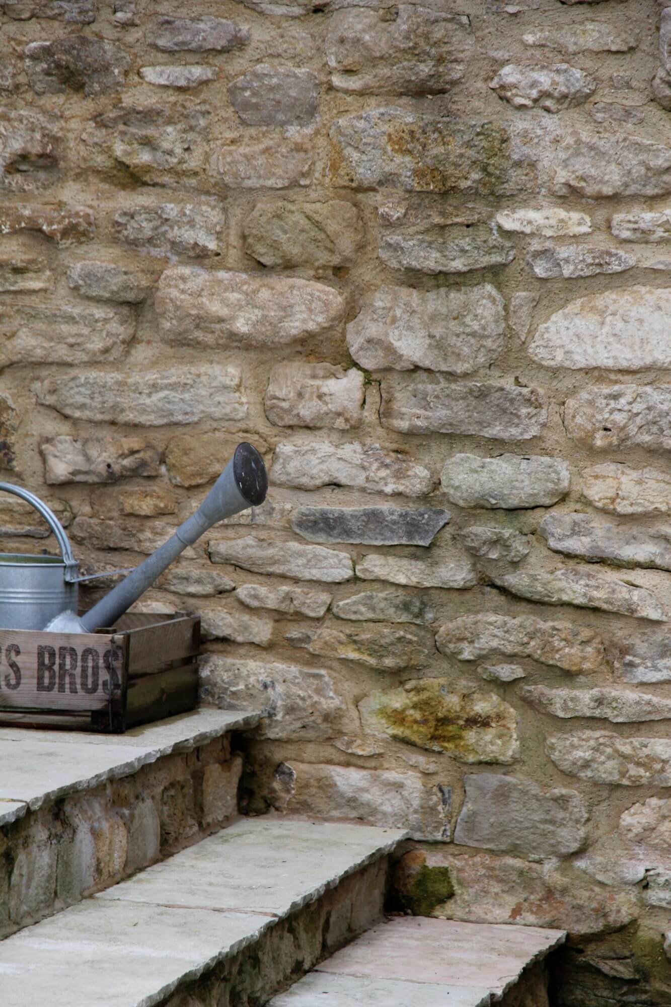 Cotswold stone wall with steps and galvanized watering can