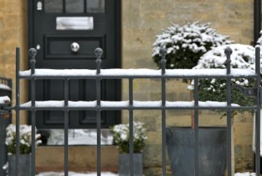 Snow fall on metal railings leading to traditional front door