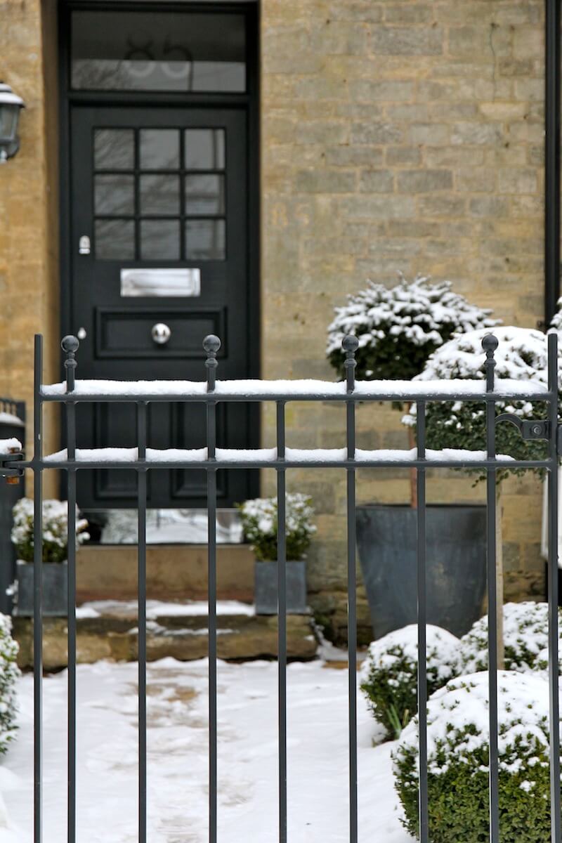 Snow fall on metal railings leading to traditional front door