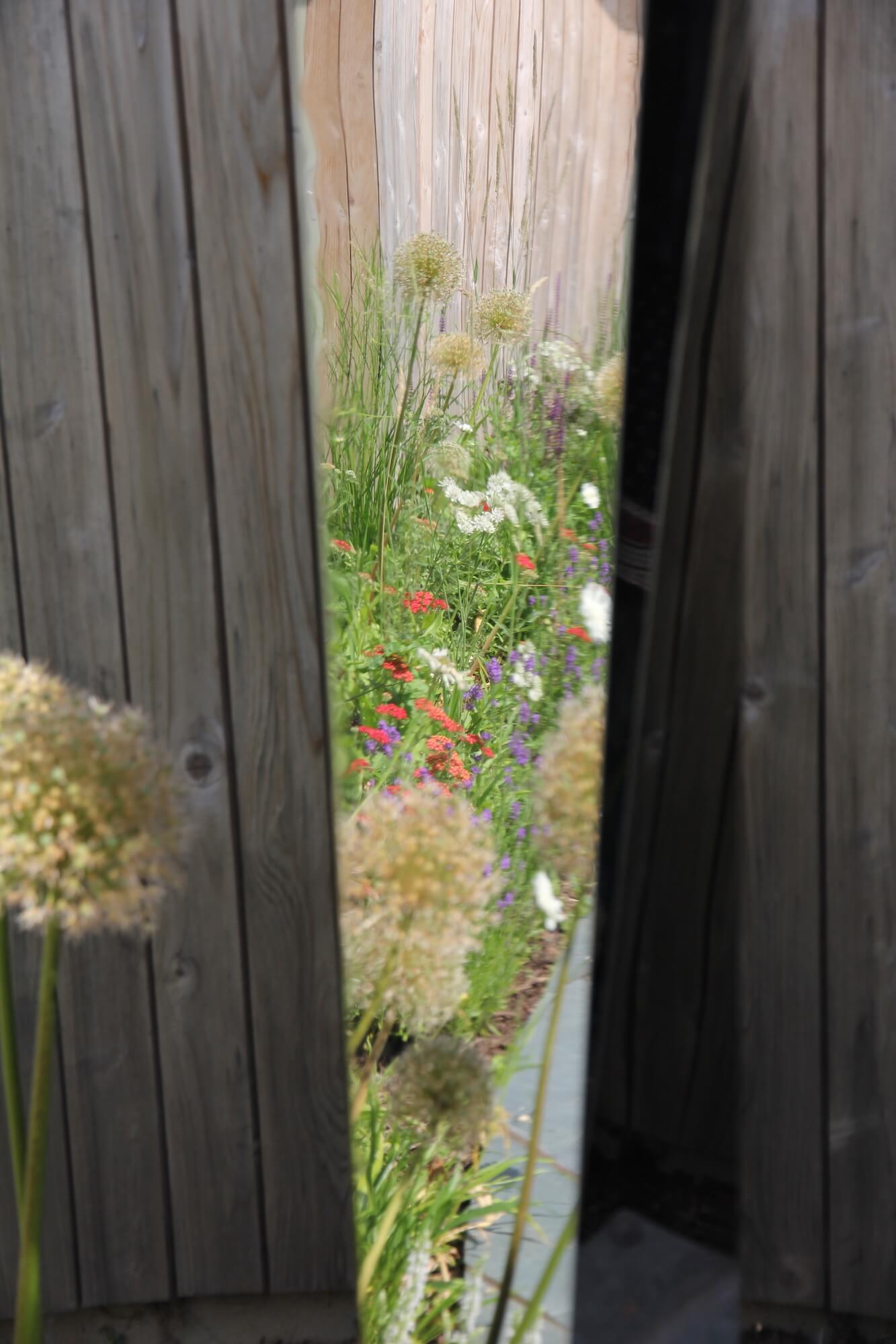 Gap between two big wooden pillars shows an abundance of meadow flowers