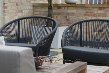 two black tub chairs in garden with olive tree