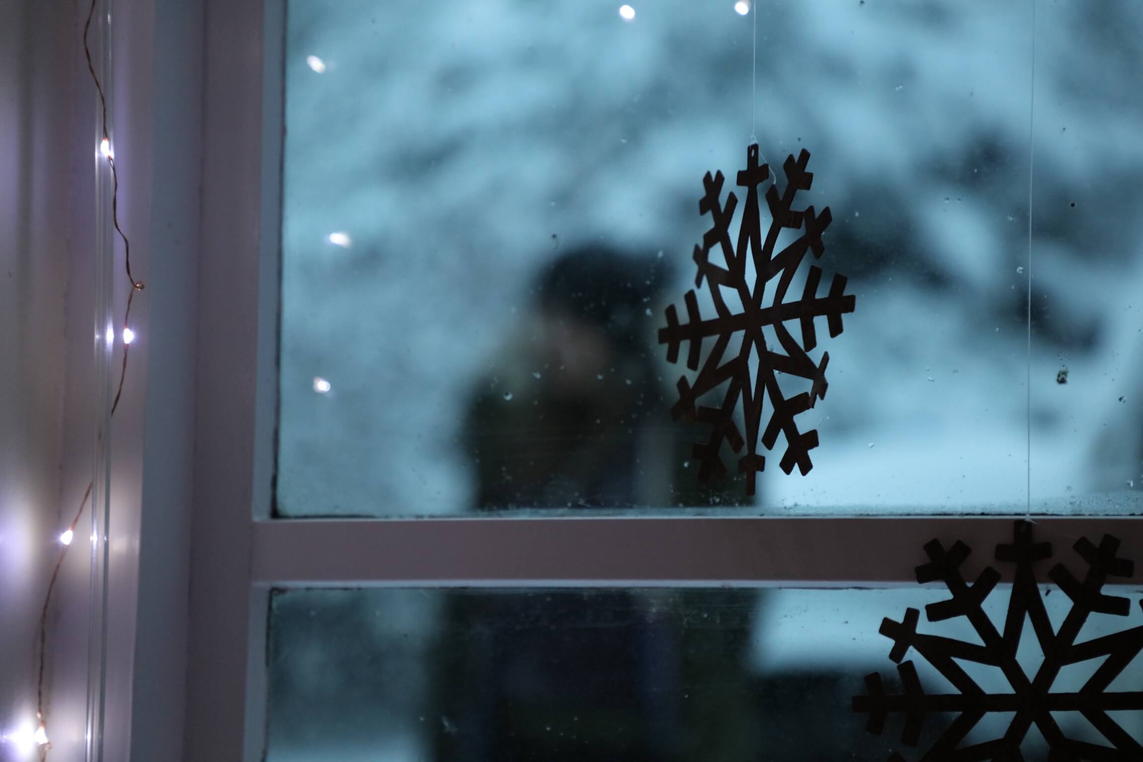 cortex snowflakes at a window with fairy lights and person walking, blue light and frosty