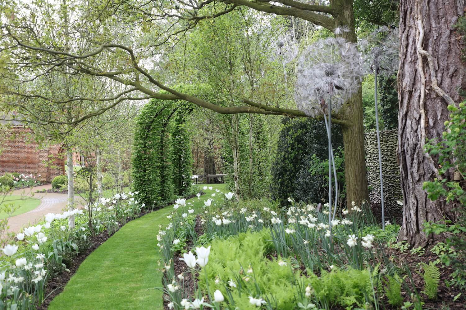 hornbeam archways with a lawn path and giant metal flower sculptures in a Oxford garden design