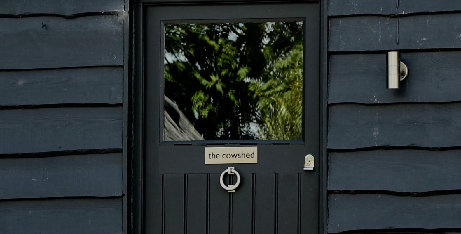 front door of a barn conversion painted in farrow & ball railings with cowshed sign