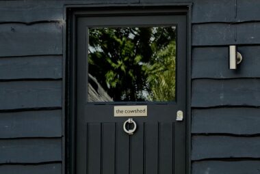 front door of a barn conversion painted in farrow & ball railings with cowshed sign