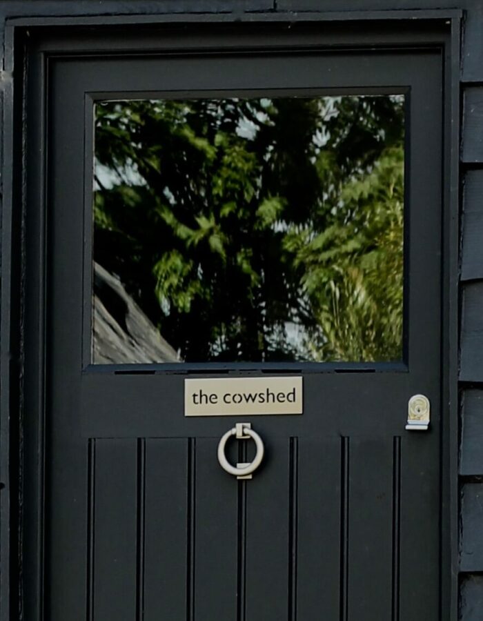 front door of a barn conversion painted in farrow & ball railings with cowshed sign